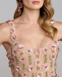 Woman wearing a floral and embellished dress with pink flowers and gold accents.