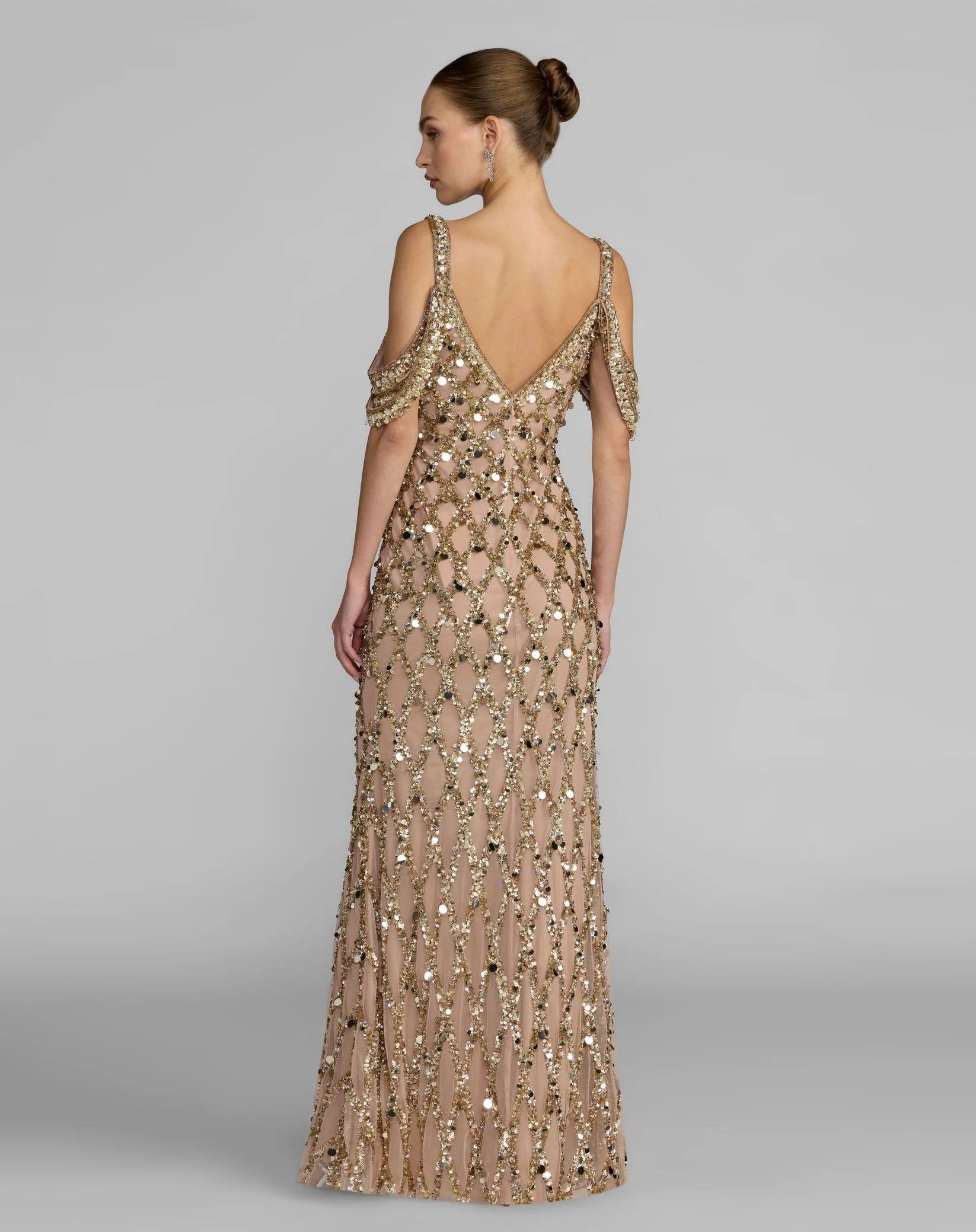 Woman wearing a long, beaded evening gown with a plain background