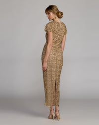 Woman wearing a gold lace dress against a gray background