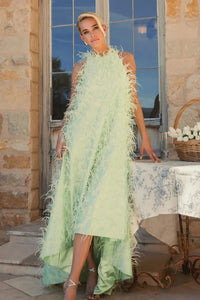 Alternate angle lifestyle view showcasing the elegant, sleeveless profile and dramatic silhouette of the feathered gown.