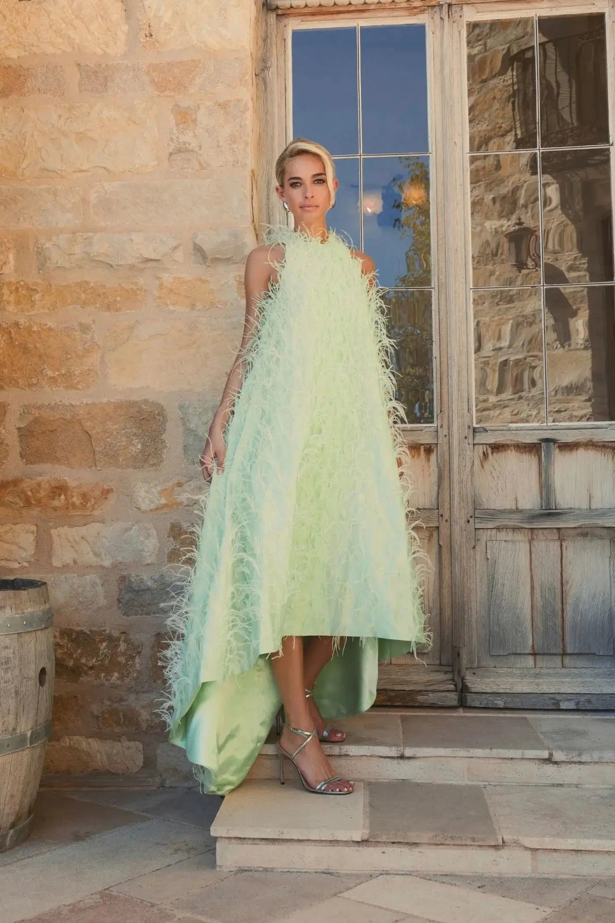 Full-length front view of the high-neck Mint satin evening gown showcasing the allover feather texture and dramatic high-low hemline.