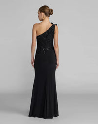 A woman modeling a black one-shoulder evening gown from the back, featuring a beaded embellished bodice and a fitted silhouette, against a light gray studio background.