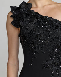Black evening gown with floral embellishments on a plain background