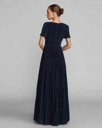 Woman wearing a long dark blue dress on a gray background