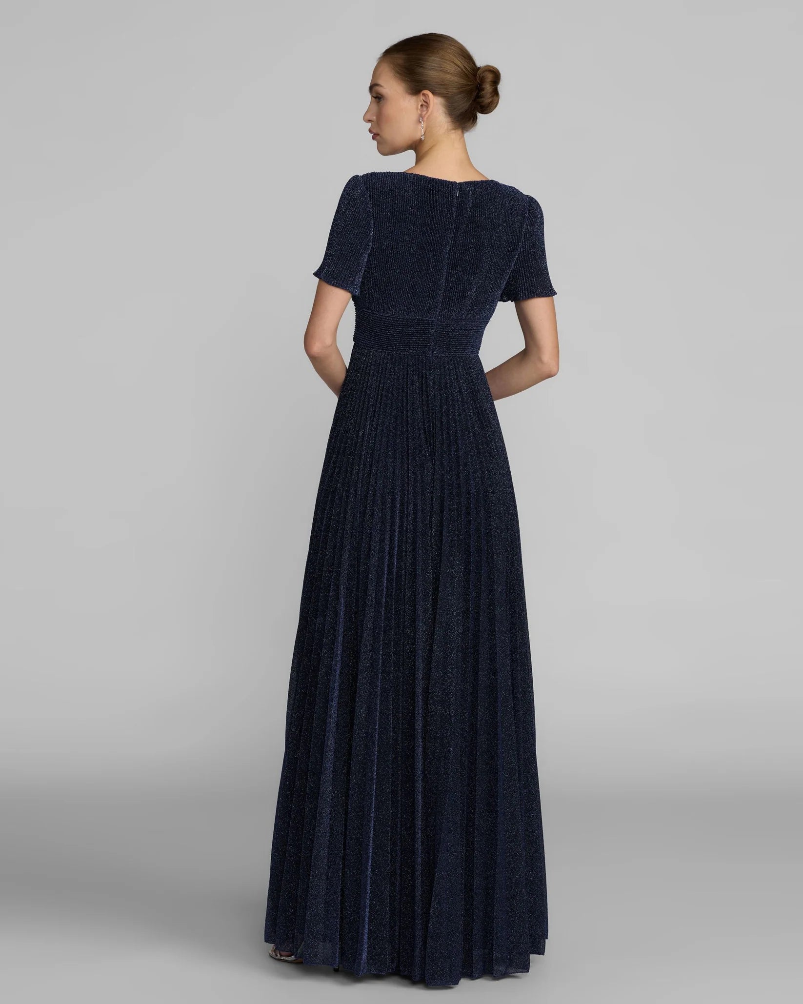 Woman wearing a long dark blue dress on a gray background