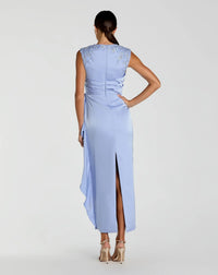 Woman wearing a light blue evening gown with a high slit on a white background