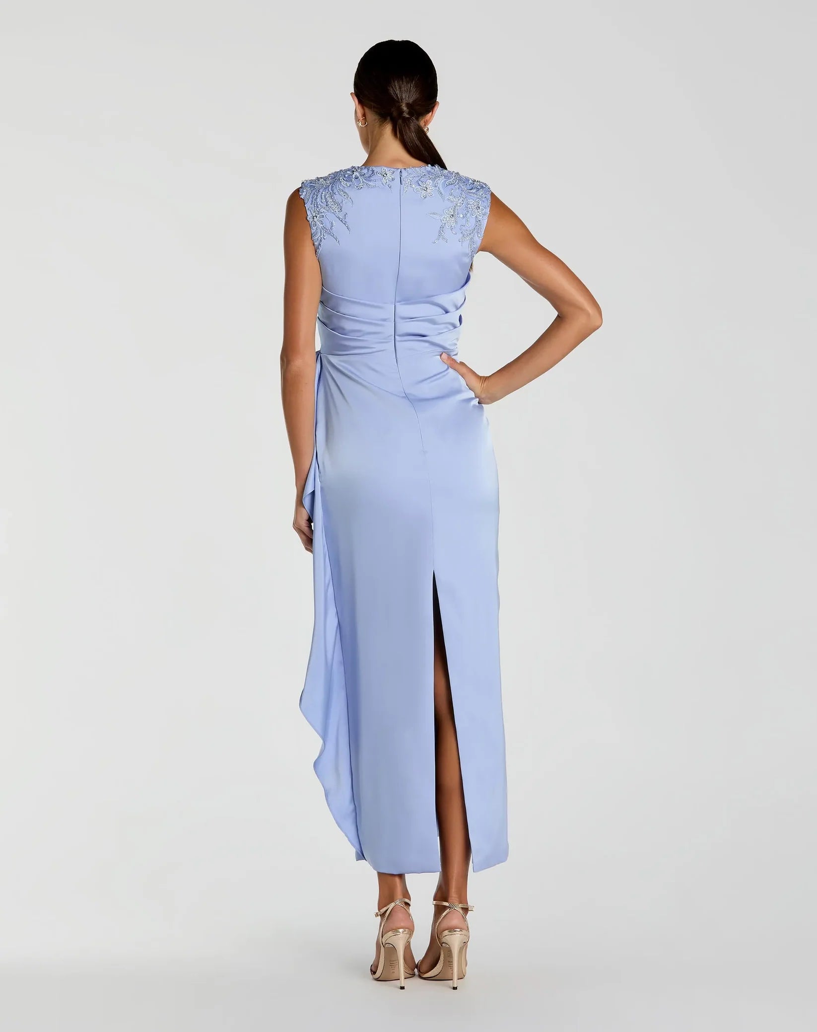 Woman wearing a light blue evening gown with a high slit on a white background
