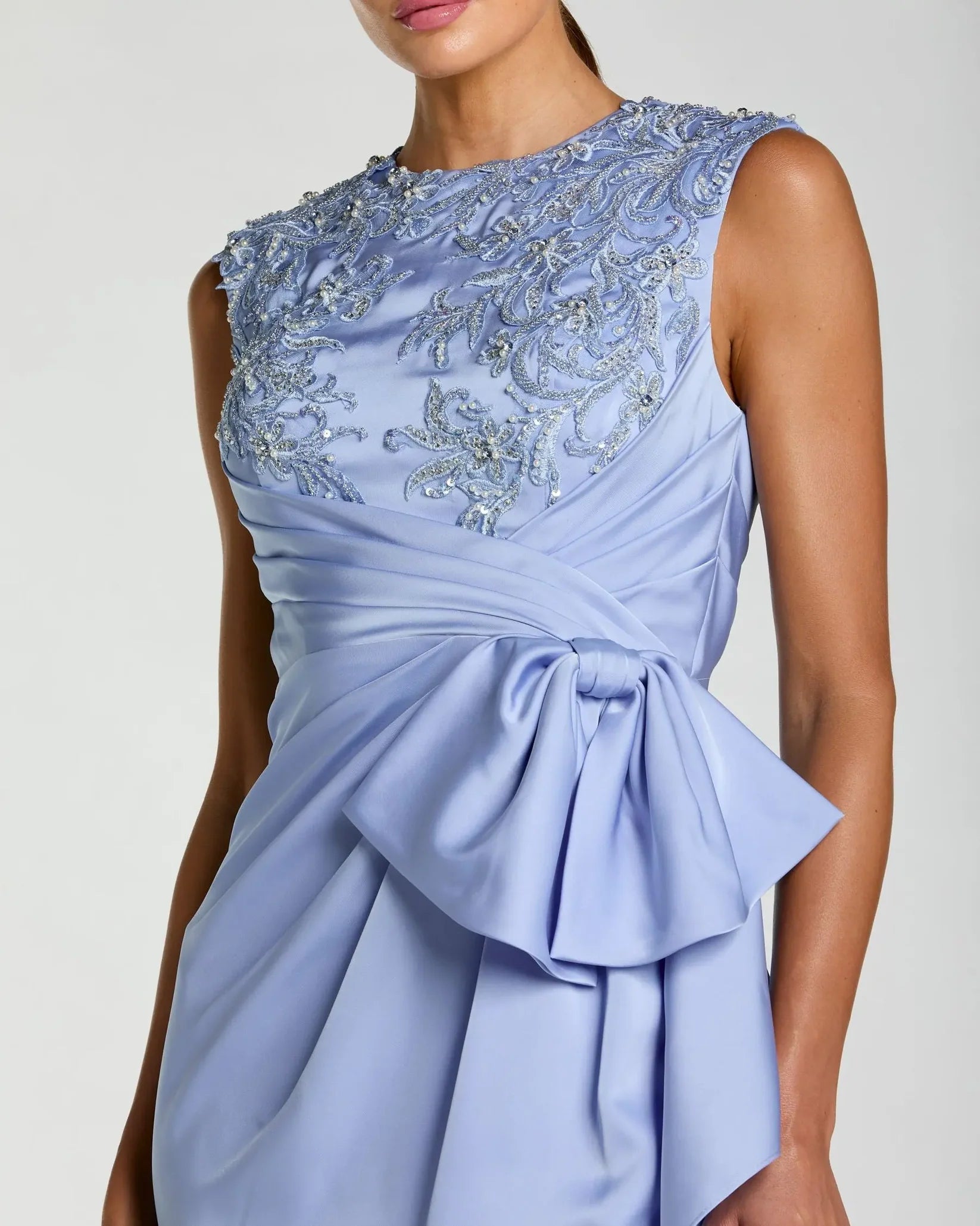 Light blue dress with intricate beading and a large bow on a plain background
