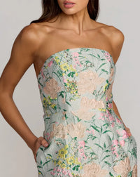 Woman wearing a strapless floral dress with a plain background