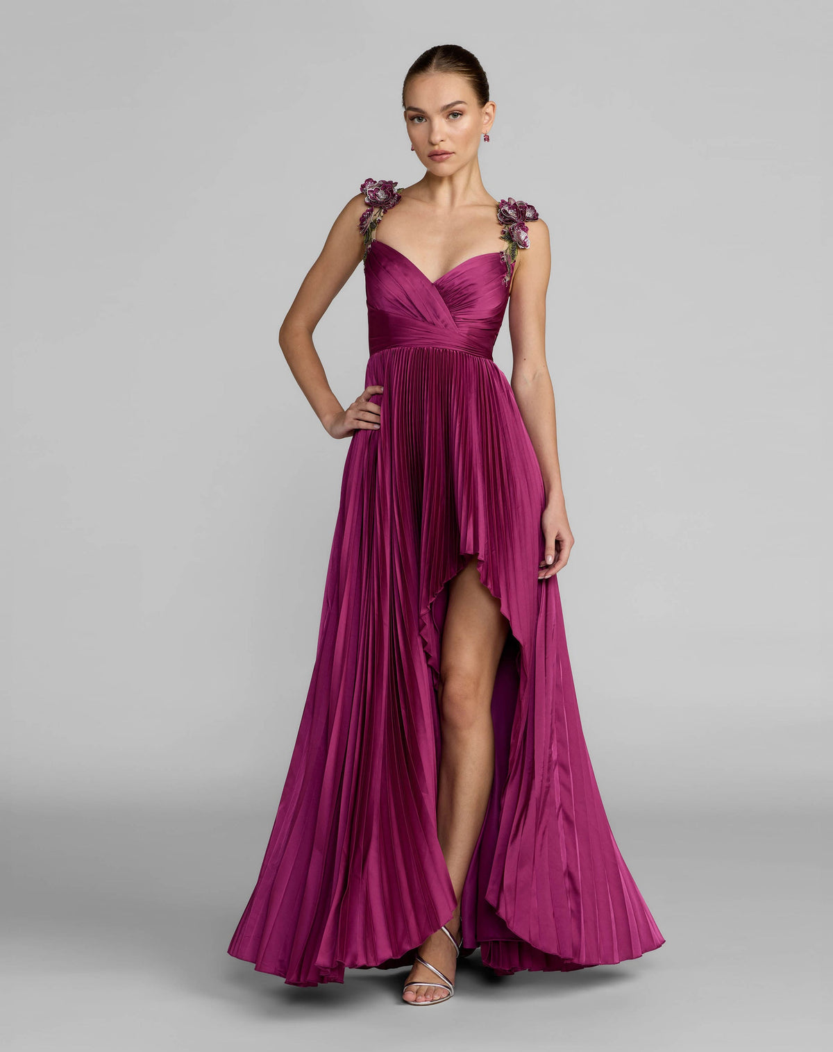 Full-length view of a model in a magenta satin high-low gown with floral straps.