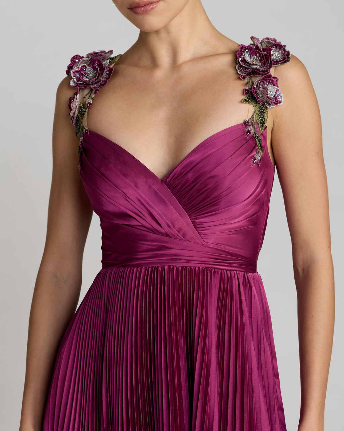 Detailed close-up of the pleated faux wrap bodice and floral strap embroidery.