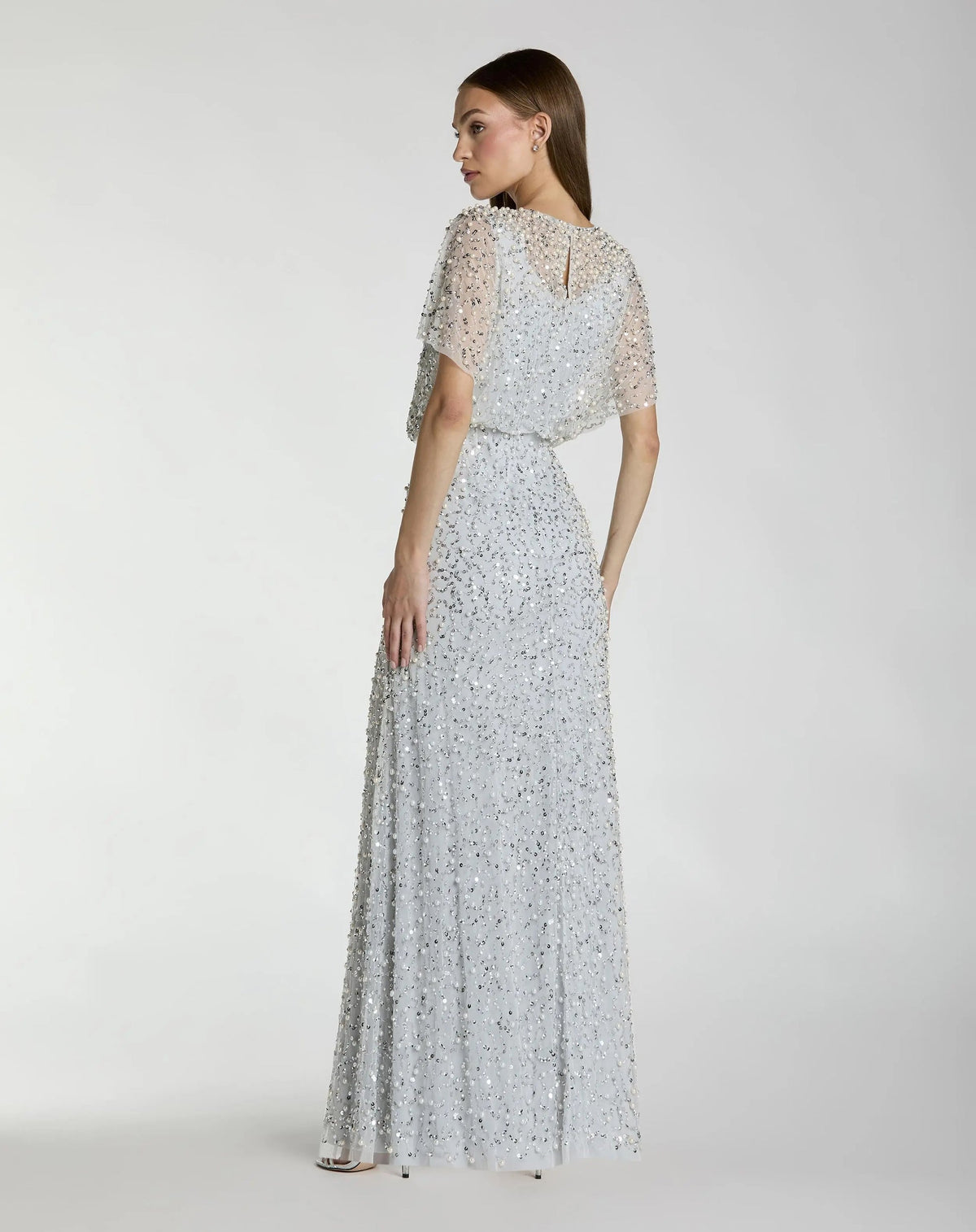 Back view of the Powder Blue formal dress highlighting the dramatic, sheer cape overlay, clean column fit, and hidden zipper closure.