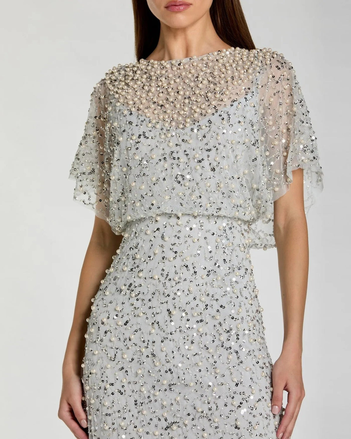 Close-up studio shot focusing on the round illusion neckline, intricate hand-applied pearls, and shimmering silver beadwork.
