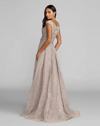 Woman wearing a beige lace evening gown against a gray background