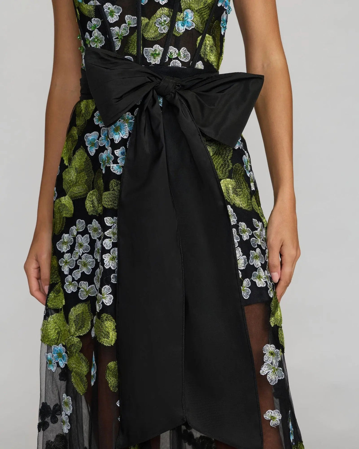 Close up the bow of model wearing Mac Duggal Black Floral Embroidered Corset Gown With Bow #21058 Blue Multi
