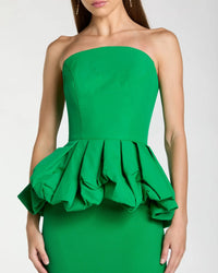 Green strapless dress with ruffled peplum on a white background