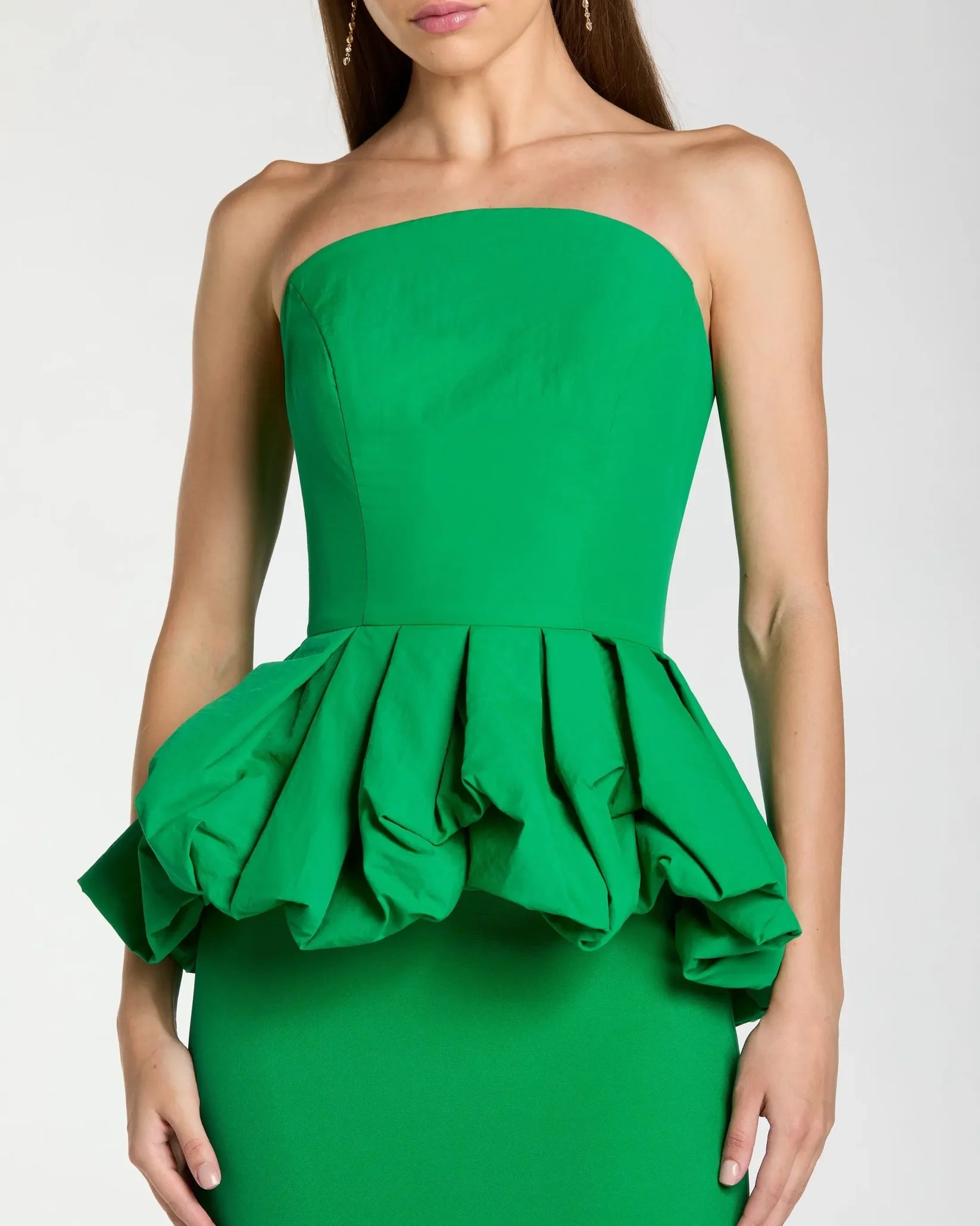 Green strapless dress with ruffled peplum on a white background
