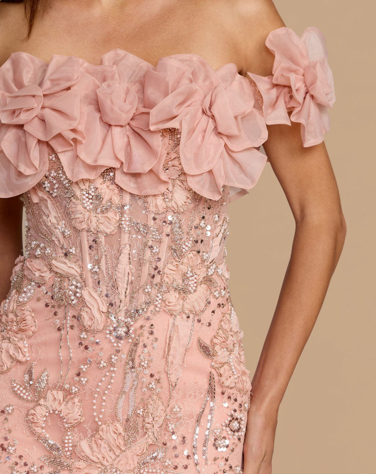 Close-up view of the off-the-shoulder neckline with 3D organza flowers on the blush embellished lace gown.