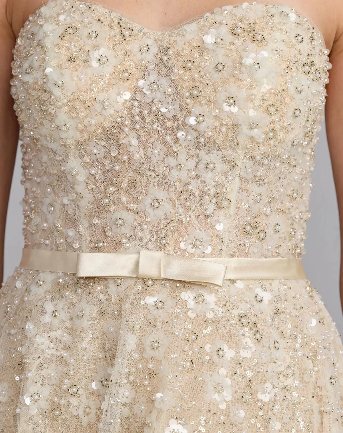 Close-up studio shot of the sweetheart bodice focusing on the exposed corset boning, delicate beadwork, and satin waist belt.