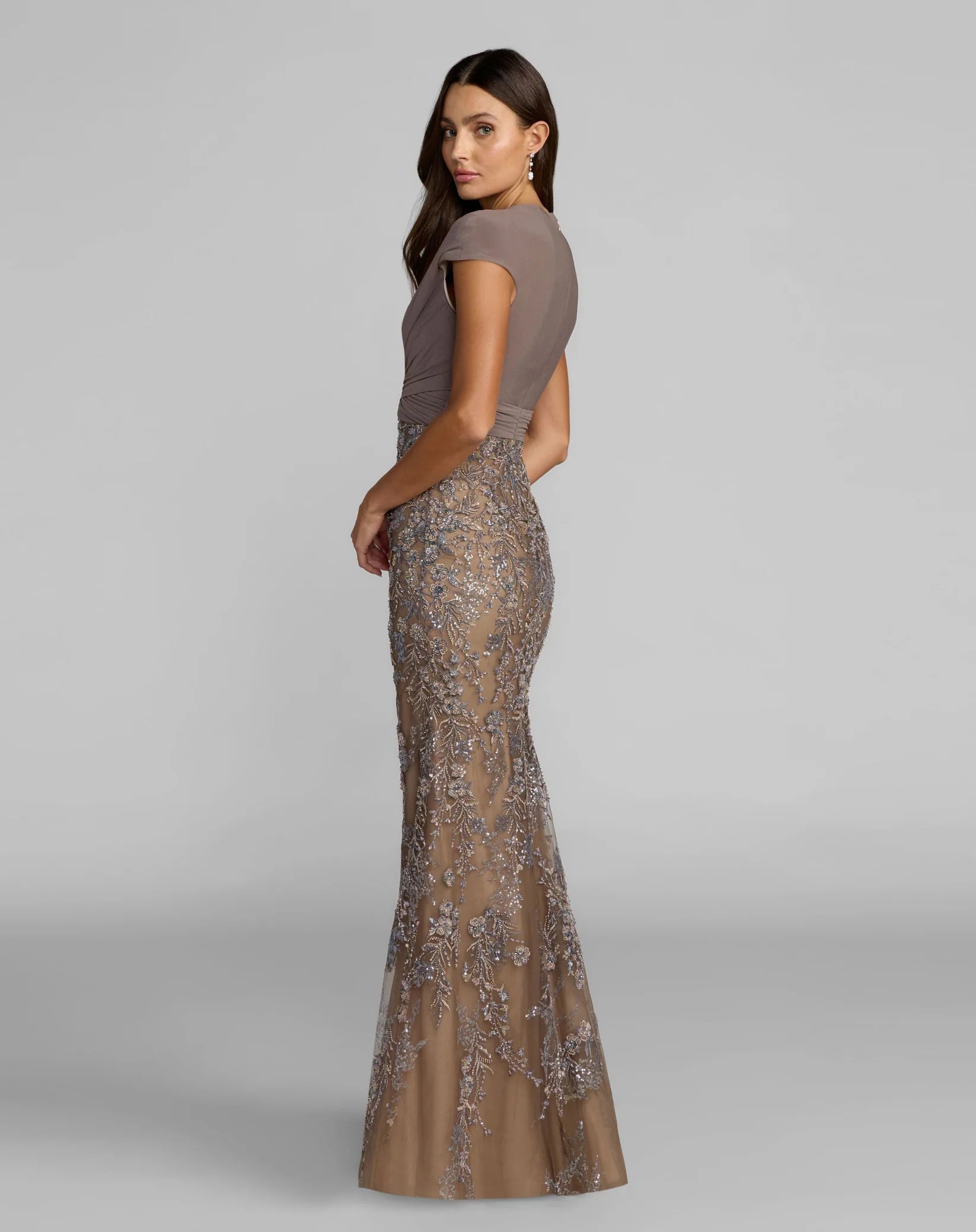 Woman wearing a brown dress with a sequined skirt on a gray background