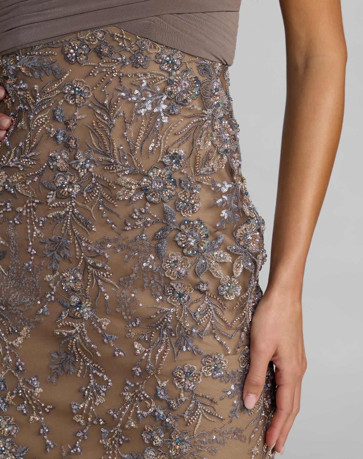 Close-up of a brown dress with floral embroidery on a plain background