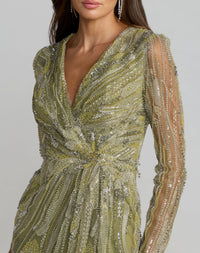 Close-up of a woman wearing a green beaded evening gown with sheer sleeves on a gray background