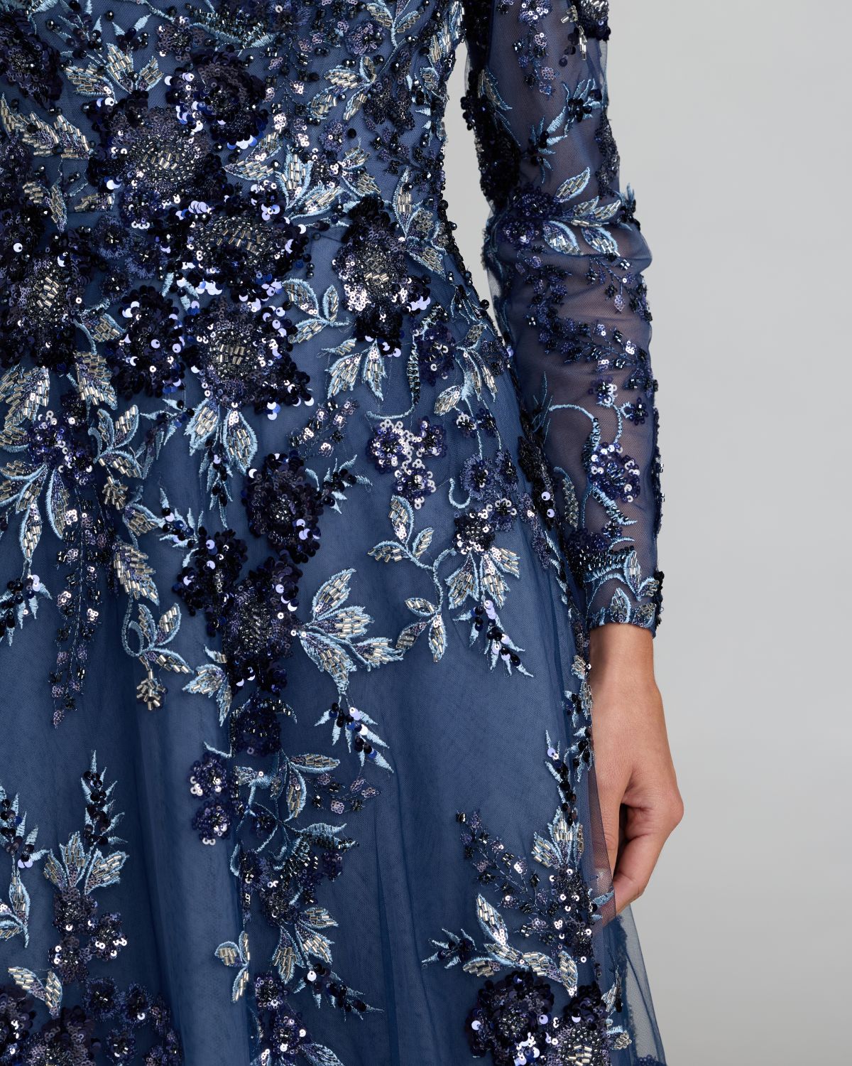 Navy blue evening gown with floral and sequin embellishments on a neutral background