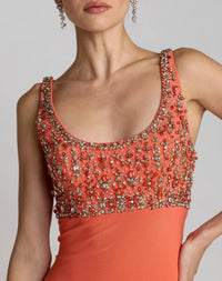 Coral evening gown with beaded top on a plain background