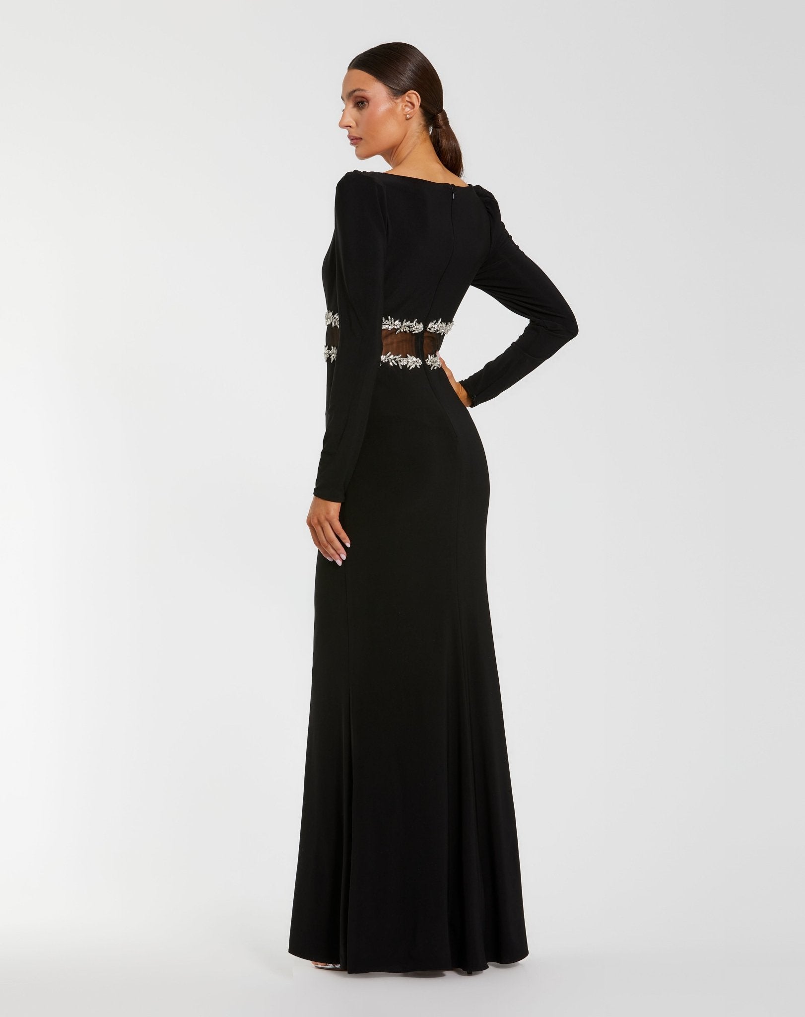 Black evening gown with long sleeves and embellishments on a white background