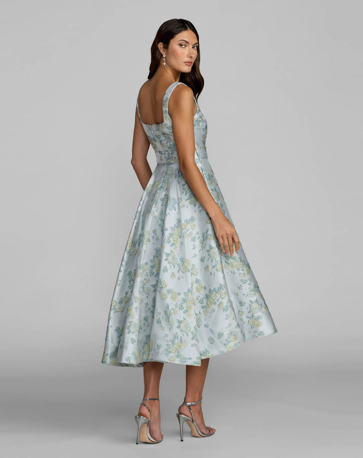 Back view of the blue-green brocade formal dress highlighting the modern square back design and clean zipper closure.