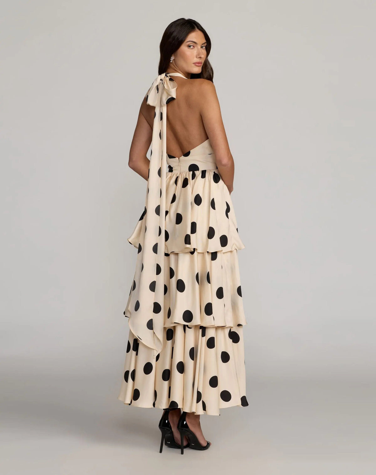 Editorial shot emphasizing the bold open back design and the flow of the tiered skirt from behind.