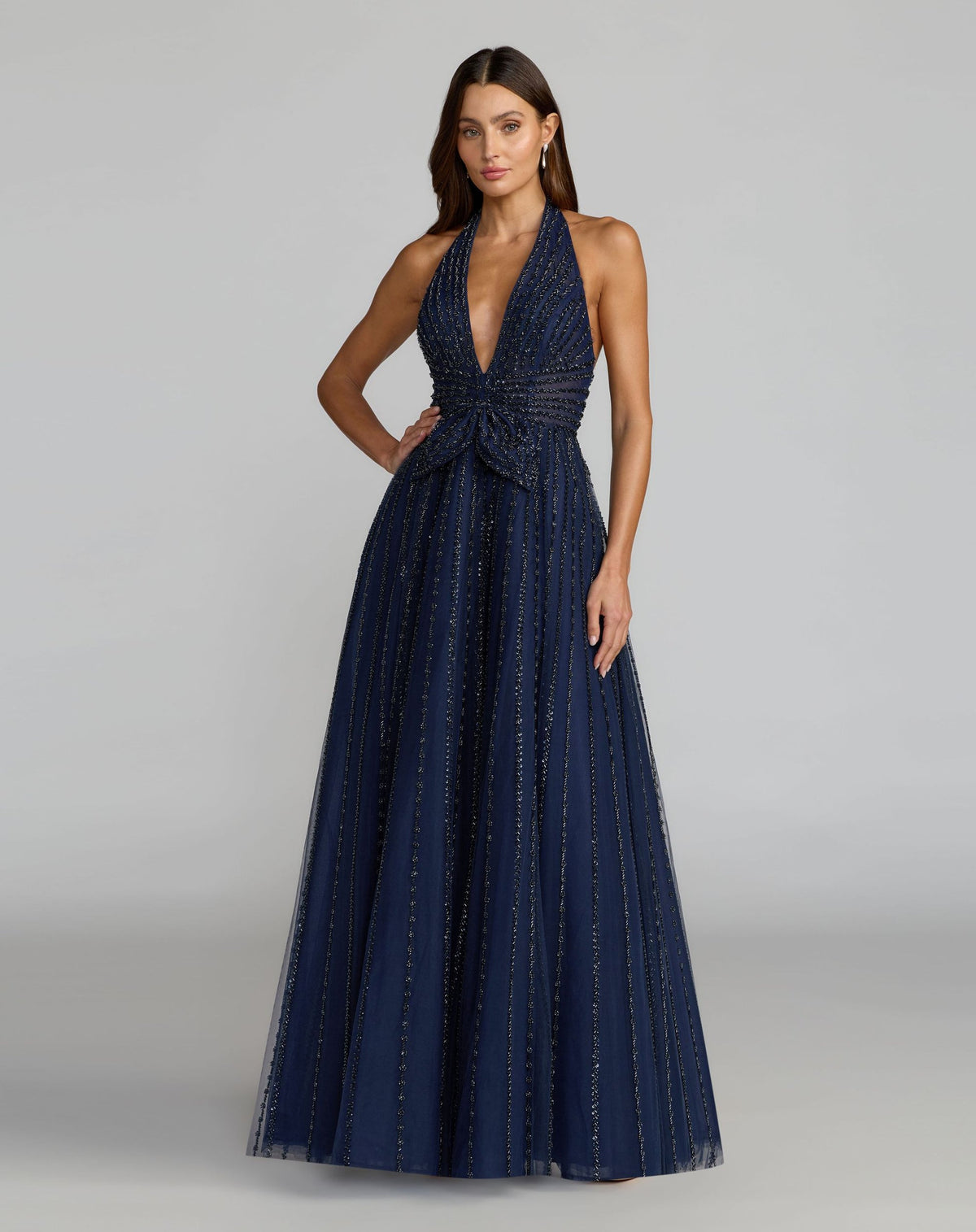 Model wearing Mac Duggal 37120 midnight plunging halter gown in a garden setting