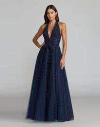 Model wearing Mac Duggal 37120 midnight plunging halter gown in a garden setting