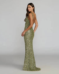A woman modeling a floor-length olive green sequined gown with a halter neckline and backless open back, photographed against a light gray studio background.