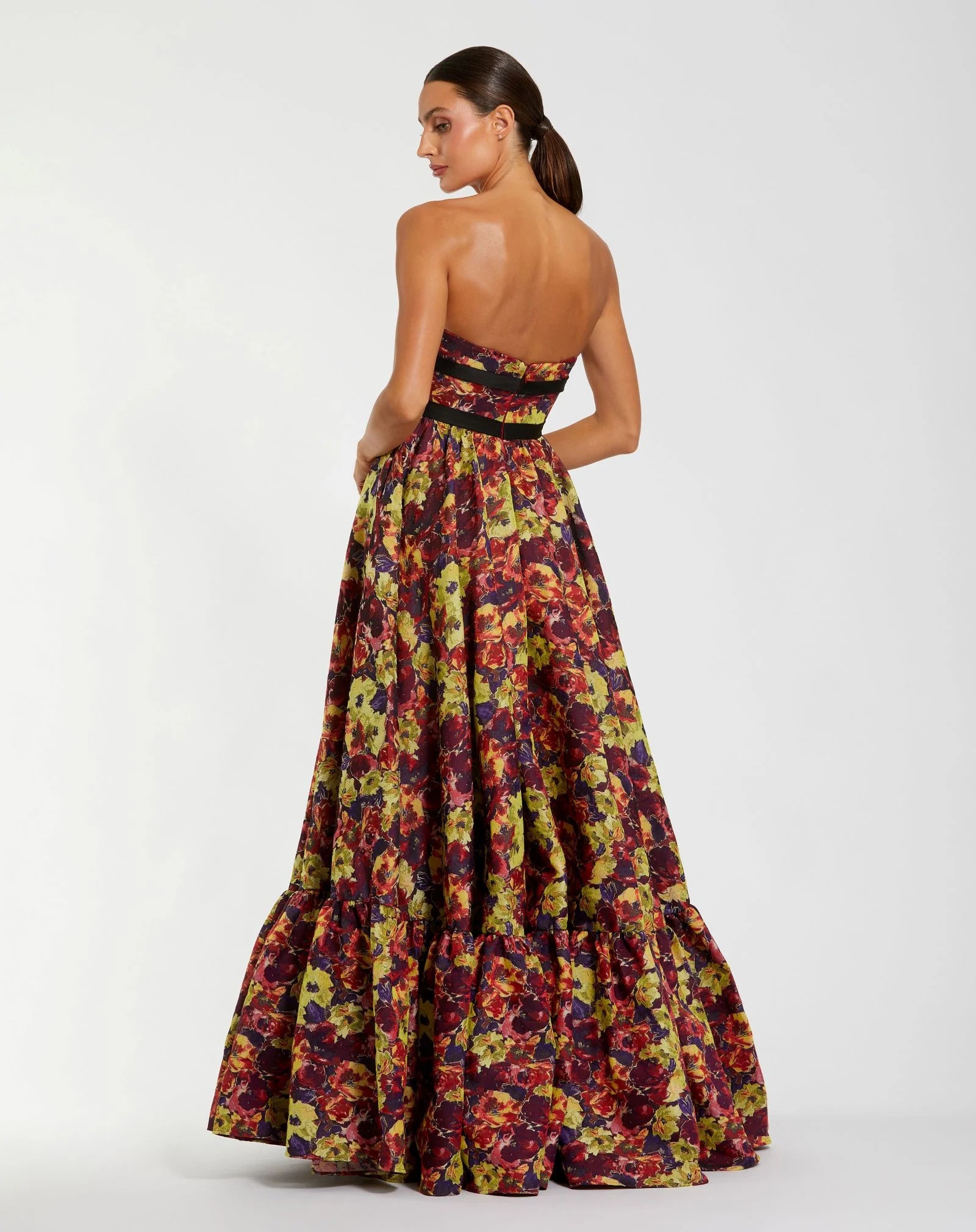 Woman wearing a strapless floral gown on a white background