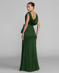 A woman modeling a floor-length dark green evening gown from the back, featuring a draped cowl neckline and a fitted silhouette, against a light gray studio background.