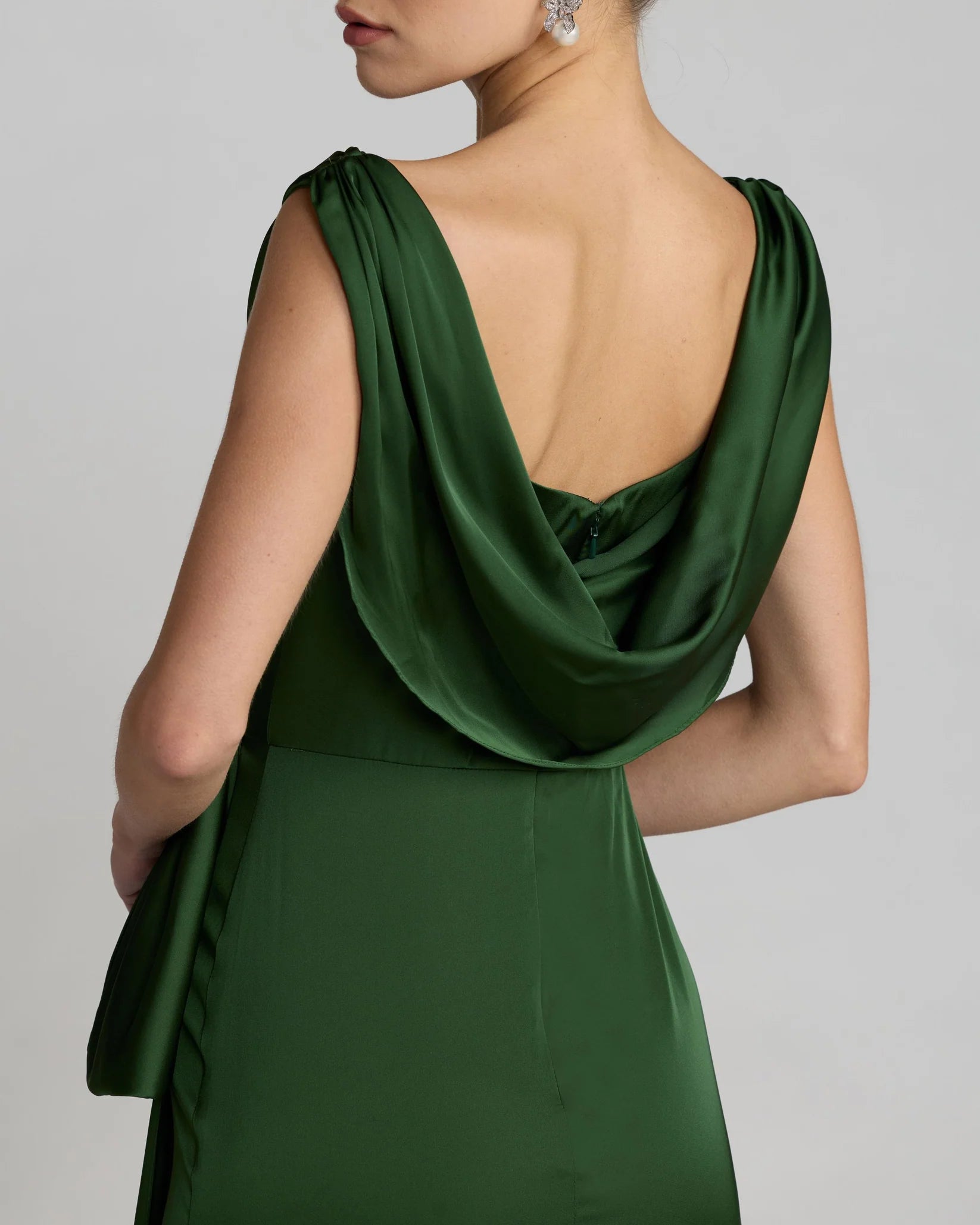 Green evening gown with a draped back design on a plain background