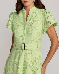 Green lace dress with a belt on a plain background