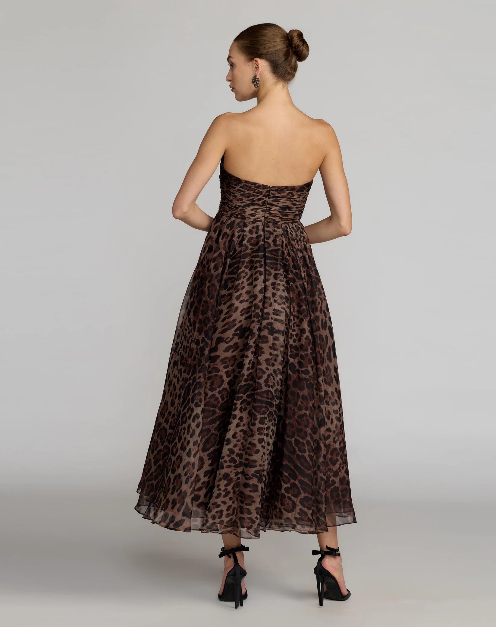 Woman wearing a leopard print dress on a plain background