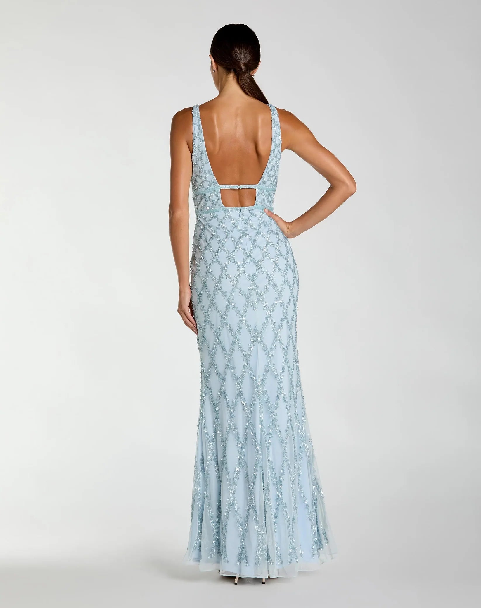 Woman wearing a light blue lace dress with a cutout back on a white background