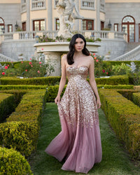 Close-up lifestyle shot of models wearing formal sequin gowns in a garden.