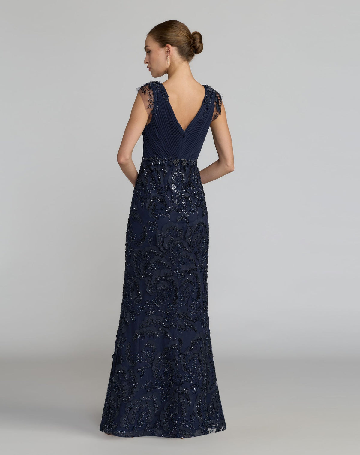 Full-length back view of a model wearing a midnight chiffon and mesh formal gown.
