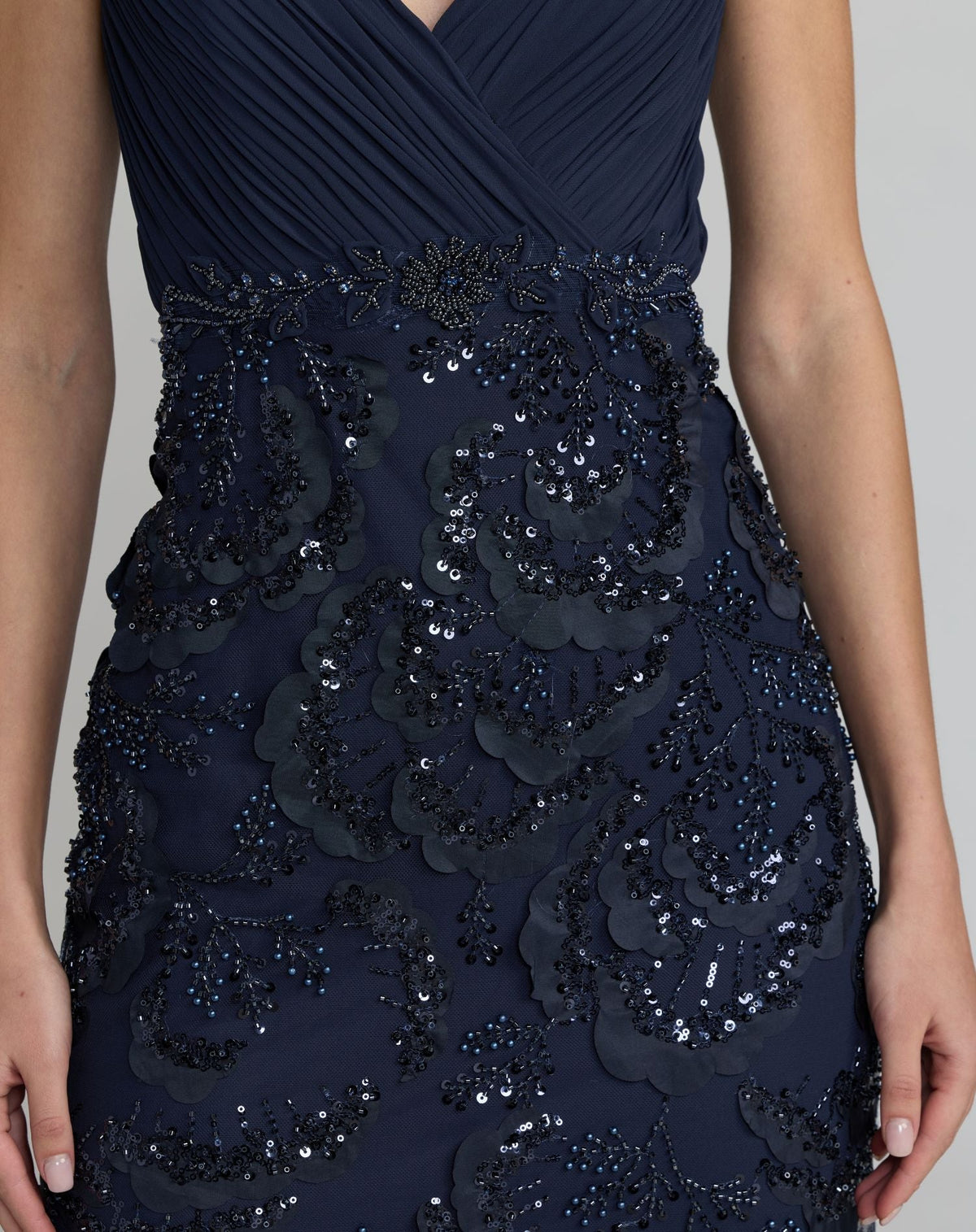 Close up view of a model wearing a midnight embellished mesh gown with a V-back design.