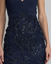Close up view of a model wearing a midnight embellished mesh gown with a V-back design.