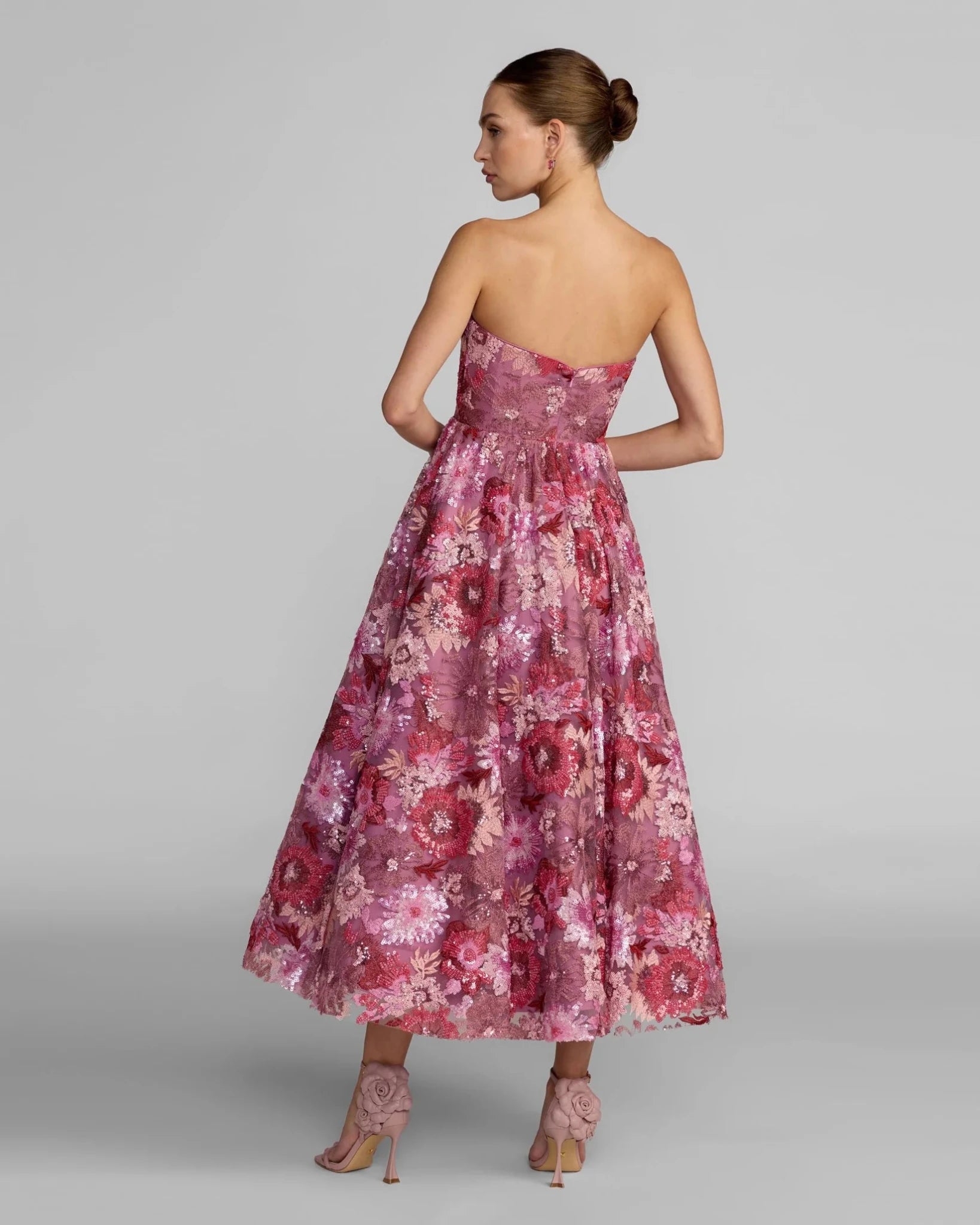Woman wearing a pink floral dress on a gray background