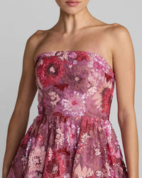 Pink strapless dress with floral embroidery on a neutral background
