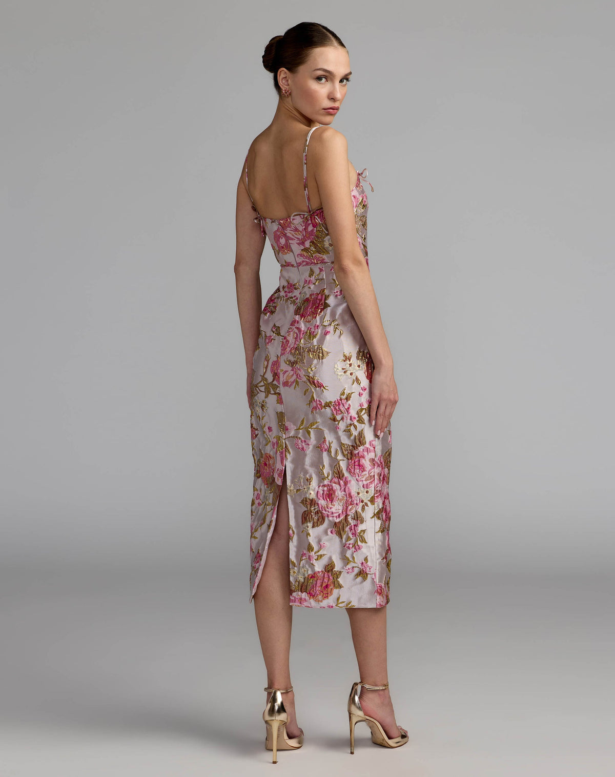 Back studio view of the fitted midi dress, highlighting the back slit, bow detail, and zipper closure.