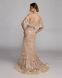 Woman wearing a sparkling evening gown with floral details on a plain background