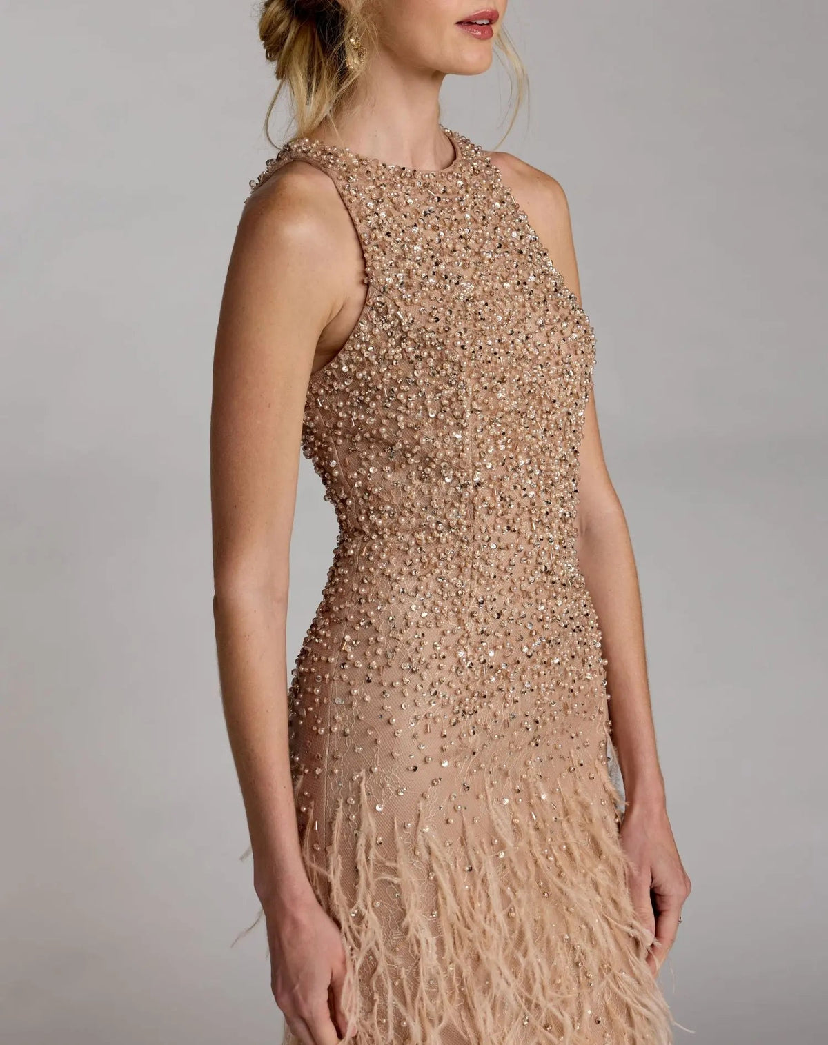 Side view of the sleeveless Porcelain high-neck evening gown featuring a beaded lace bodice and a dramatic feathered skirt.