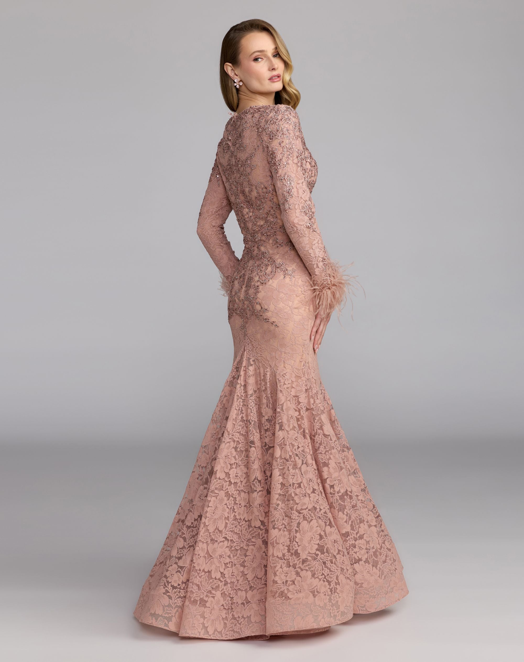 Woman wearing a long, elegant lace dress against a gray background